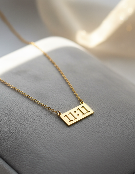 Gold necklace with a bar pendant, displaying the inscription "11:11" know as angels number engraved on its surface.