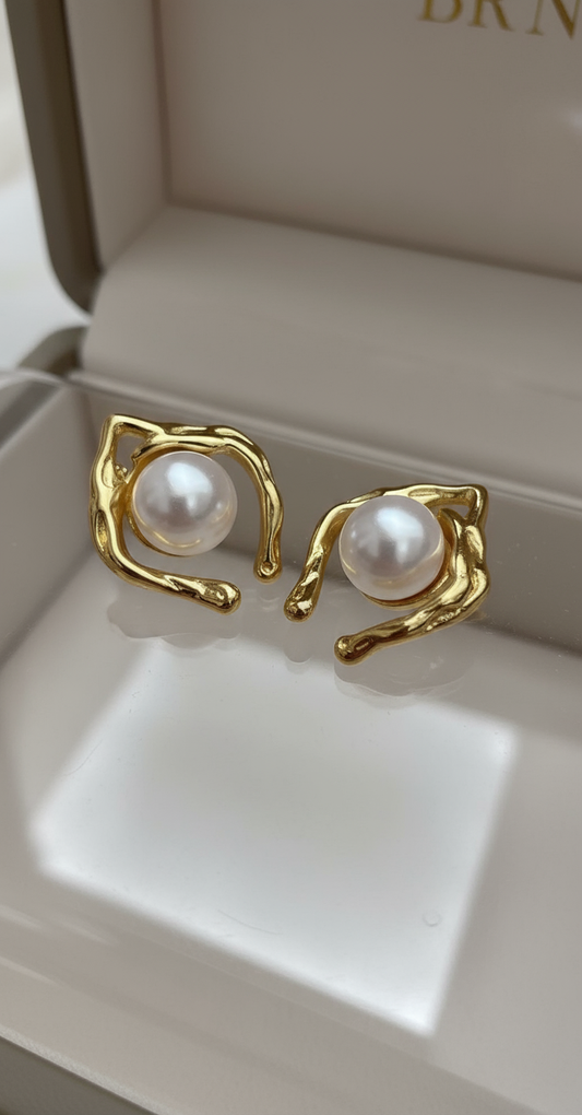 Gold abstract-shaped stud earrings featuring round white pearls in a sculpted frame design.