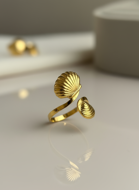 Gold shell-shaped ring on a light surface with a blurred background.