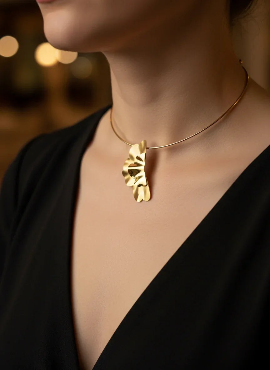 Gold choker necklace neck piece featuring a hammered, abstract floral-shaped pendant.