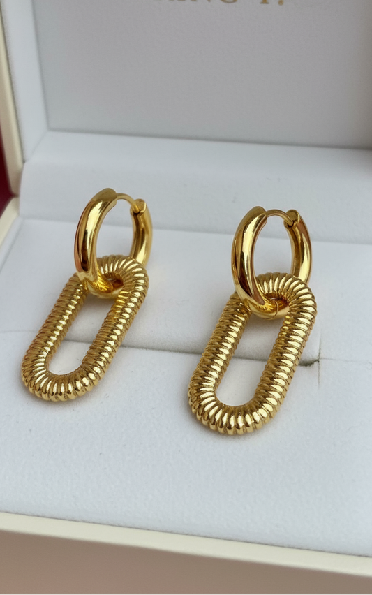 Shiny gold hoop earrings with ribbed oval link design, modern textured finish.
