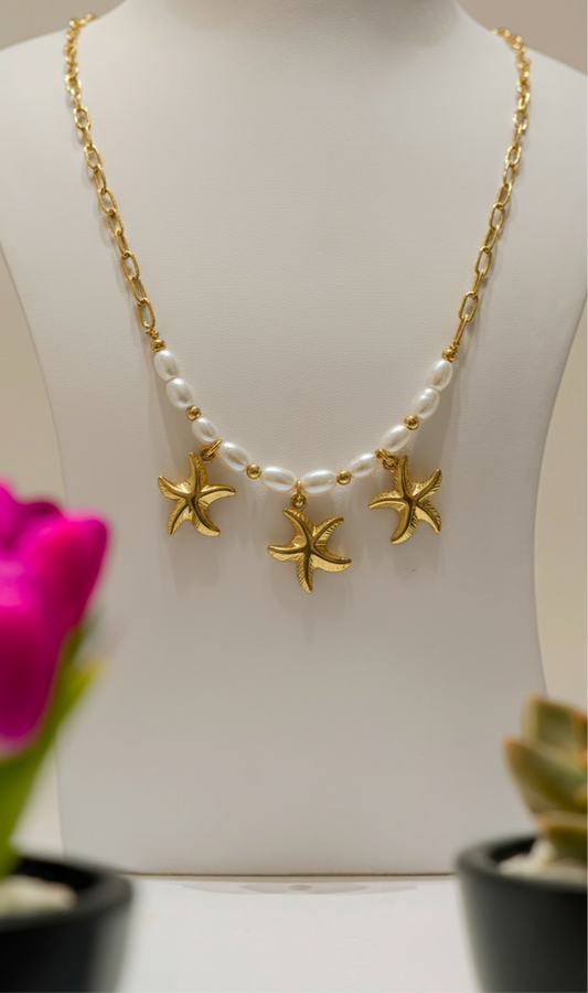 A gold necklace featuring three starfish with pearl charms, elegantly designed for a unique and nature-inspired look.