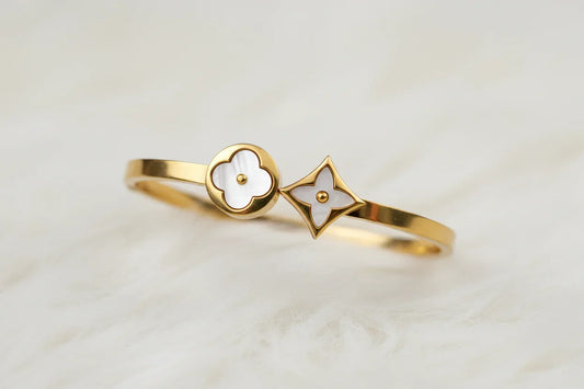 A beautiful gold bracelet featuring two charming four white clover leaf, perfect for adding a touch of floral elegance to any outfit.