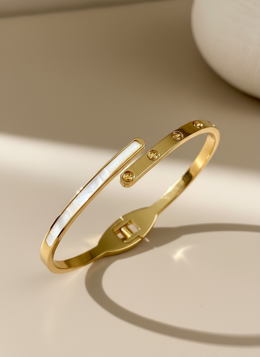 Elegant gold open bangle bracelet with mother of pearl inlay and screw design detail.