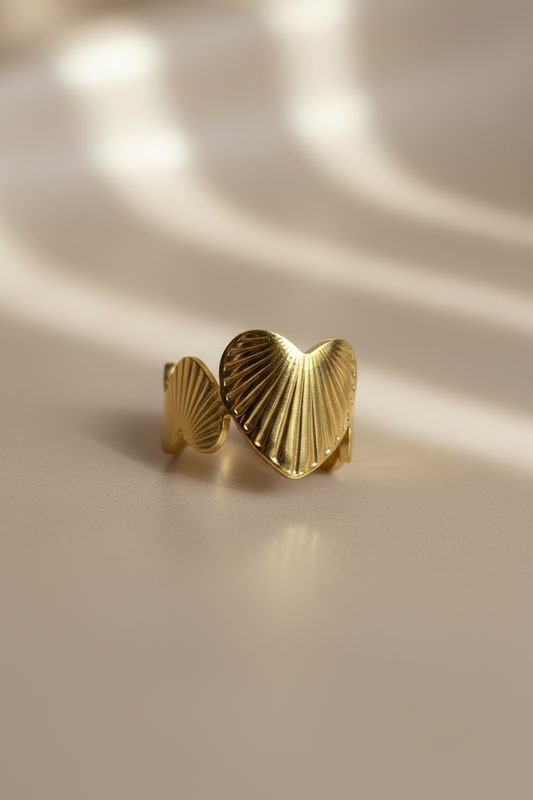 Gold adjustable ring with textured shell heart design and open band style.