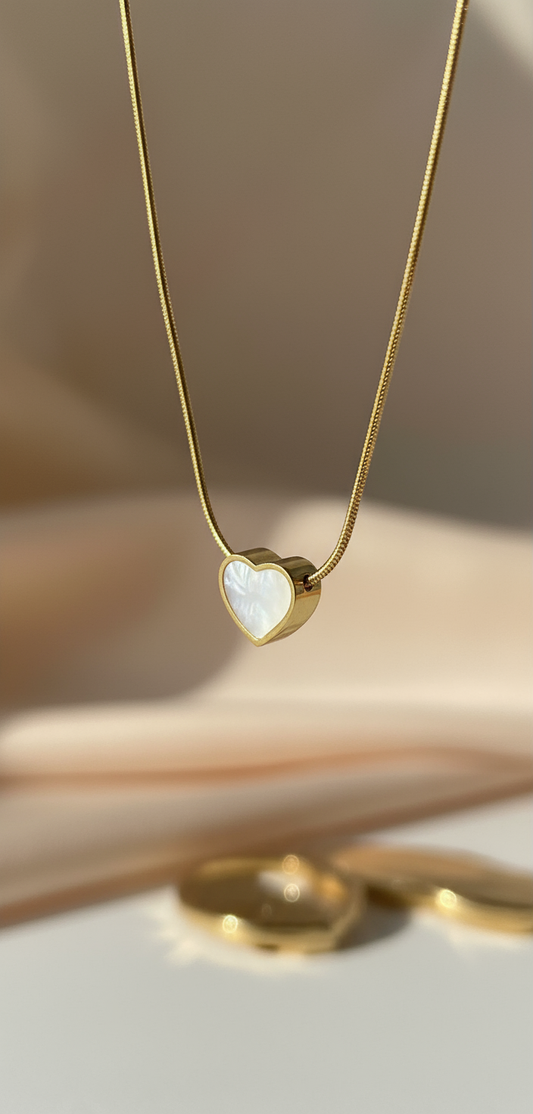 Gold necklace with a heart-shaped pendant on a neutral background