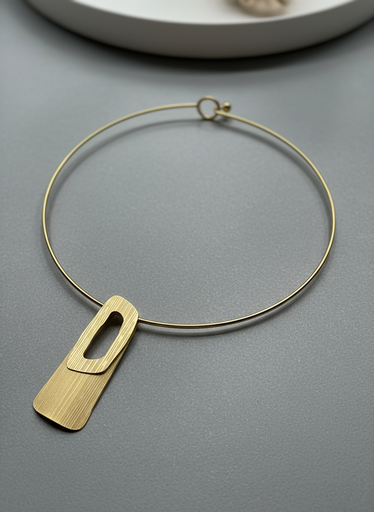 Minimalist gold choker necklace featuring a brushed rectangular geometric pendant with cutout design.